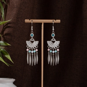 Detail of Bohemian tassel earrings with colorful beads on a vintage metal display stand