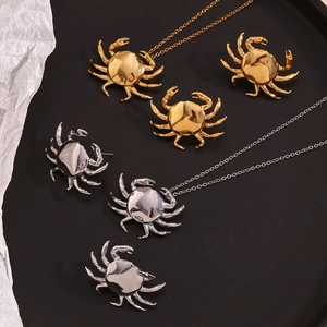 Detalle de collares y pendientes de cangrejo en oro y plata sobre una bandeja negra