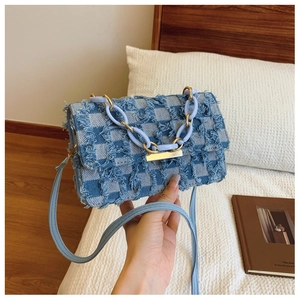 Détail d'un sac bandoulière en jean à carreaux avec franges et grosse chaîne bleue