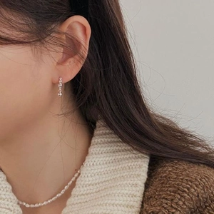 Close-up of elegant silver ball dangle earrings and minimalist pearl necklace on a model
