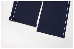 Détail du pantalon de survêtement bleu marine avec bandes blanches et ourlets cousus