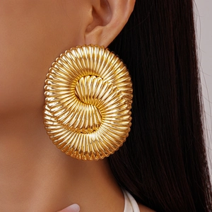Gros plan de boucles d'oreilles en métal doré à texture spirale sur un modèle