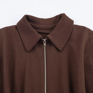 Detail of dark brown knit jacket featuring a metal zipper and textured fold-over collar