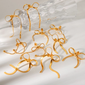 Macro shot of 18k gold stainless steel bow earrings with snake chain fringe details