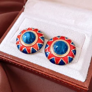 Vintage gold-rimmed round earrings with red and blue resin enamel and starburst design