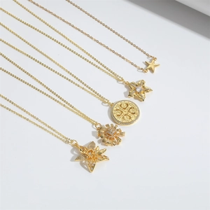 Detail of five gold necklaces featuring star, sunflower, and coin pendants on white background