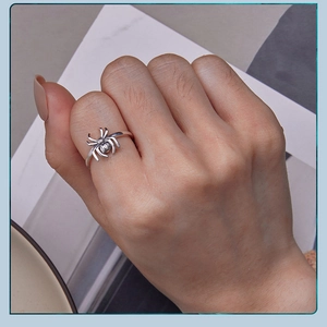 Macro detail of a vintage S925 silver spider ring worn on finger with intricate textures