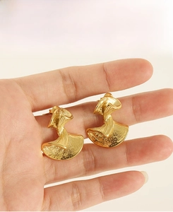 Detail of gold fan-shaped earrings with unique hammered texture and irregular design