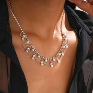 Détail d'un collier argenté à franges avec perles et strass sur vêtement noir
