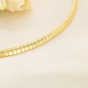 Detailed macro view of gold-tone geometric textured chain links with metallic luster