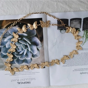 Detailed view of golden butterfly charms on a delicate metal chain belt for women