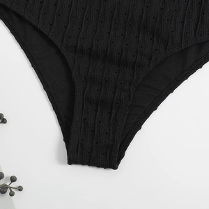 Macro detail of black ribbed fabric with eyelet texture and fine stitching on bikini bottom