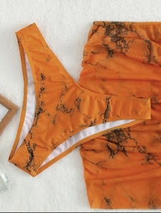 Detailed view of orange marble print bikini bottom and matching mesh ruched mini skirt