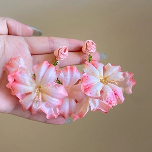 Close-up of pink gradient floral earrings with elegant green bead tassels and studs