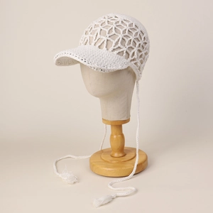 Detail of white crochet hollow-out baseball cap with long fringe chin strap ties