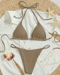 Flat lay of brown ribbed halter bikini top and high-cut bottom with vacation props