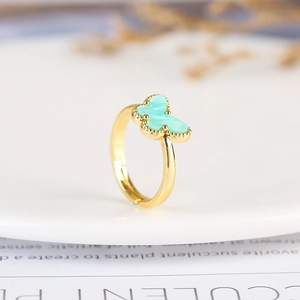 Macro shot of an adjustable gold butterfly ring with mint green enamel detailing