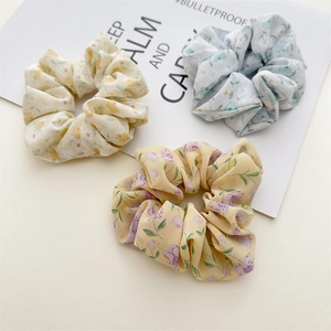 Three chiffon floral scrunchies in yellow and blue colors shown on a minimalist card