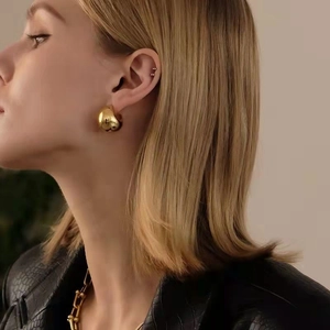 Elegant gold drop-shaped hollow earrings with a high-polished finish on female model