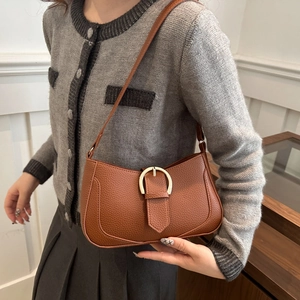 Detail of brown lychee texture leather shoulder bag with golden horseshoe buckle