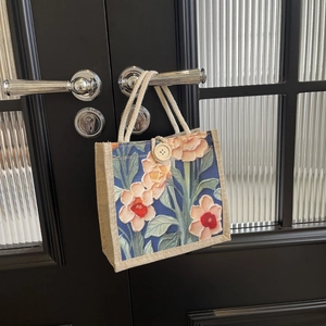 Close-up of linen tote bag featuring a floral print and rustic cotton rope handle