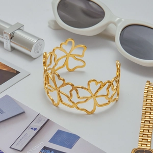 Elegant gold hollow flower open bangle with polished finish on a fashion magazine background