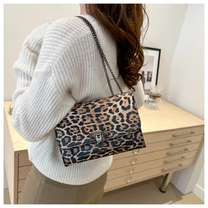 Close-up of leopard print shoulder bag with chain strap worn over a white sweater