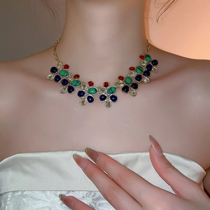 Close-up of vintage gold necklace with colorful gemstones worn on a model's neck