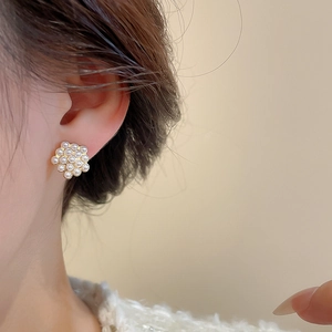 Close-up of elegant pearl cluster flower earrings worn on ear with soft gold plating