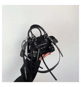 Detail of black patent leather motorcycle bag with silver rivets and tassels