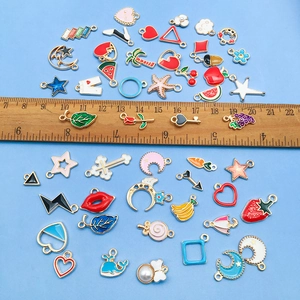 Assorted colorful enamel jewelry charms in star and heart shapes on a light blue background