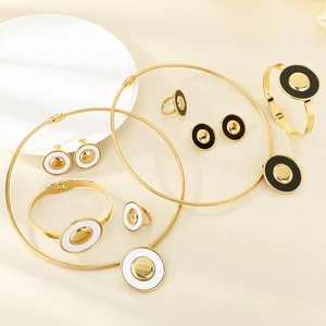Golden stainless steel jewelry set with black and white round charms on silk fabric
