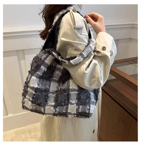 Detail of tweed tote bag with black and white plaid pattern and fringe texture