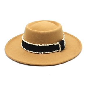 Detail of camel wool felt hat featuring black ribbon trim and delicate pearl beads
