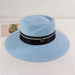 Detail of light blue woven sun hat with black ribbon and golden T metal buckle