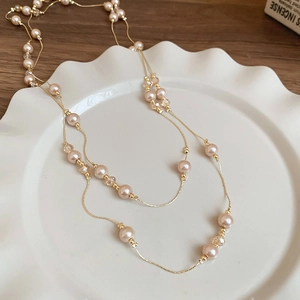 Détail de perles roses et billes dorées sur un long collier superposé élégant