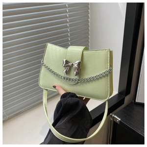 Detail of light green faux leather shoulder bag with silver bow buckle and metal chain