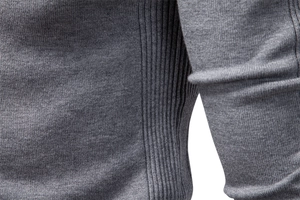 Detailed close-up of grey knitted sweater fabric with ribbed side stitching craft