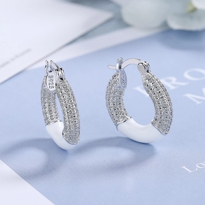 Macro shot of silver S925 earrings with pavé zircons and white enamel detail