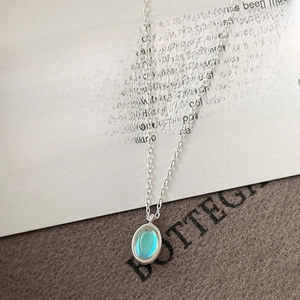 Macro view of sterling silver necklace with oval colorful blue gemstone pendant