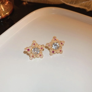Vue macro de boucles d'oreilles étoile dorées avec cristal clair et détails roses