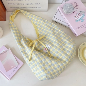 Detail of yellow and blue plaid canvas tote bag with a bow tie and decorative label