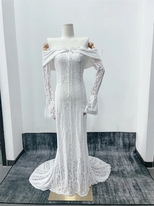 Detail of white lace off-shoulder wedding dress with long flared sleeves and fishtail hem