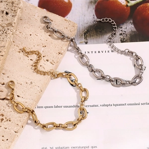 Detail of 14K gold and silver chunky O-link chains on stone and magazine background