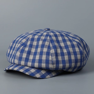 Detailed view of a blue and grey plaid newsboy cap with woven linen texture and button top