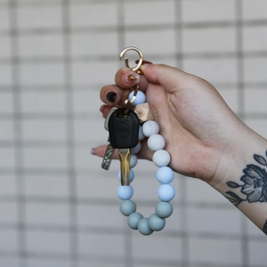 Detailed view of silicone beaded bracelet keychain with blue and grey beads and gold ring