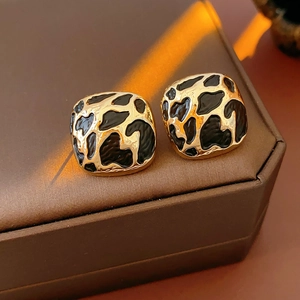 Gros plan de boucles d'oreilles léopard dorées sur cuir marron avec lumière douce