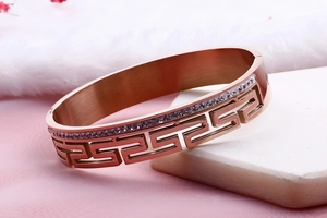 Detail of rose gold stainless steel bangle with Greek key pattern and cubic zirconia