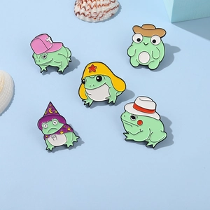 Five cute enamel frog pins with wizard and cowboy hats on a soft blue background