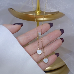 Detailed macro view of Y-shaped gold necklace with baguette zircon and shell heart charms